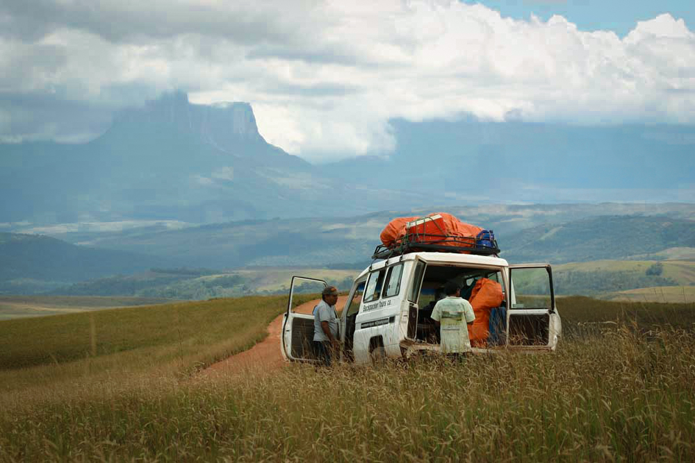 Expedition vehicle loaded with gear on a dirt road approaching Mount Roraima across the Gran Sabana, Venezuela